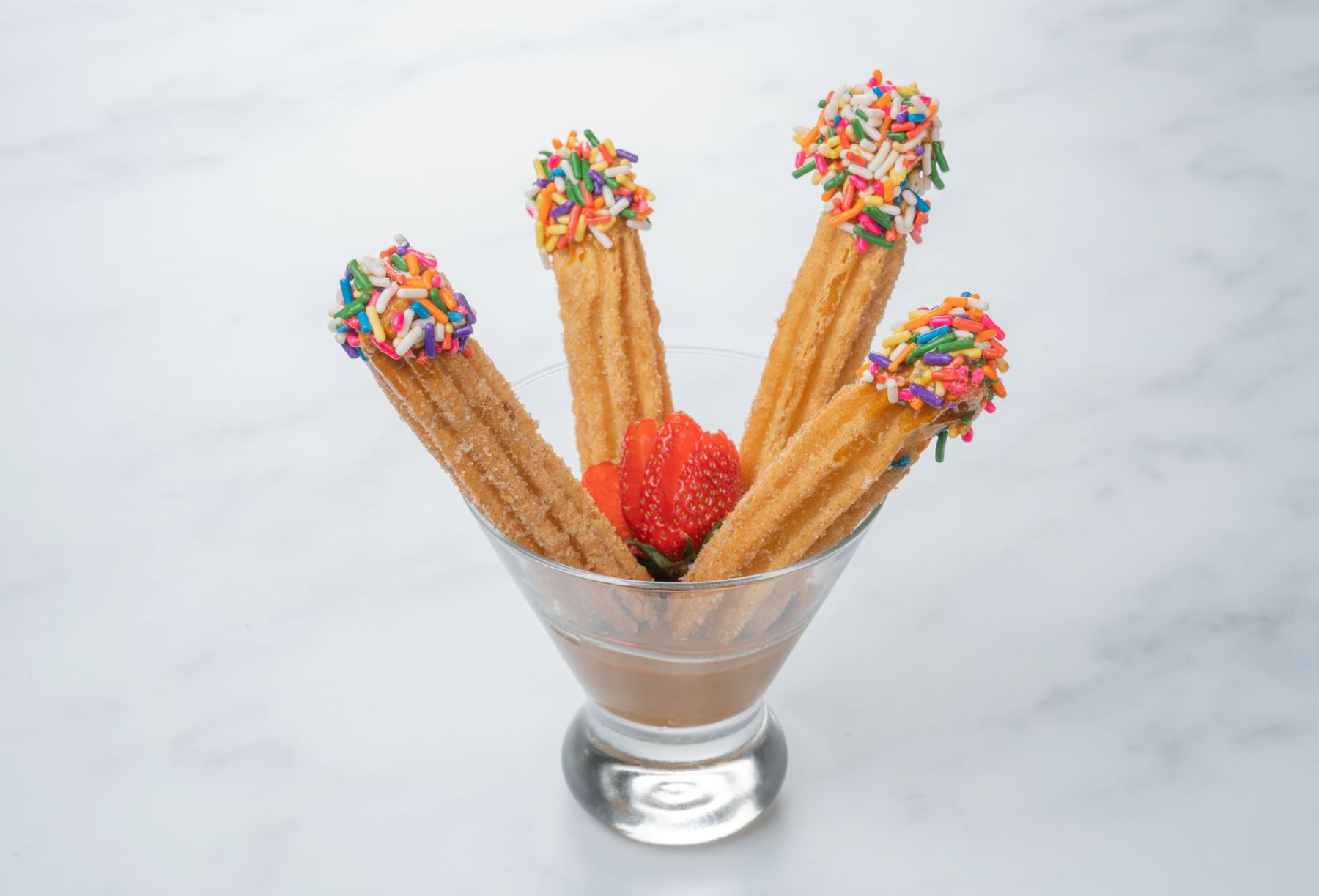 Churros com doce de leite e granulado colorido